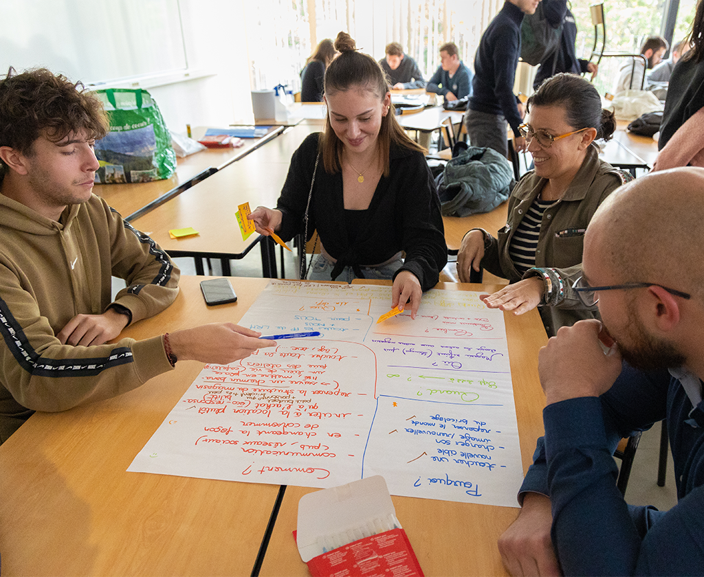 Des étudiants de l'IAE sont assis autour d'une table et travaillent ensemble lors des ateliers de l'innovation.