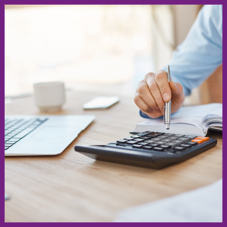 Une personne est assise à son bureau avec devant lui un ordinateur, une calculatrice et un agenda.