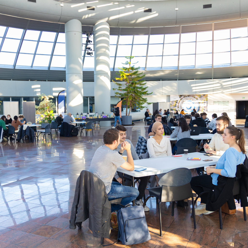 Des étudiants sont assis autour de plusieurs tables et participent à ESTER Technopole aux ateliers de l'innovation de l'IAE Limoges.