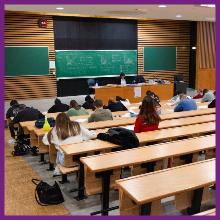 Plusieurs étudiants sont installés dans un amphithéâtre et participent à un examen. Une personne est installée en face d'eux et les surveille.