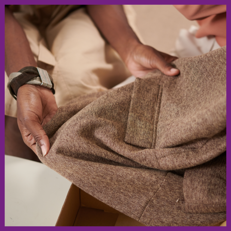 Une femme tient et touche un manteau qu'elle a entre ses mains.