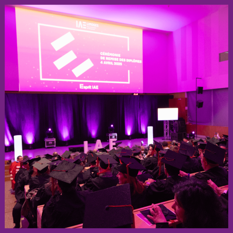 Vue de la salle comble lors de la cérémonie de remise des diplômes de l’IAE Limoges, le 4 avril 2025. Les diplômés, en toges et coiffés de mortiers, assistent à l’événement dans un amphithéâtre décoré de lumières violettes. En fond, un écran géant affiche le visuel officiel de la cérémonie.