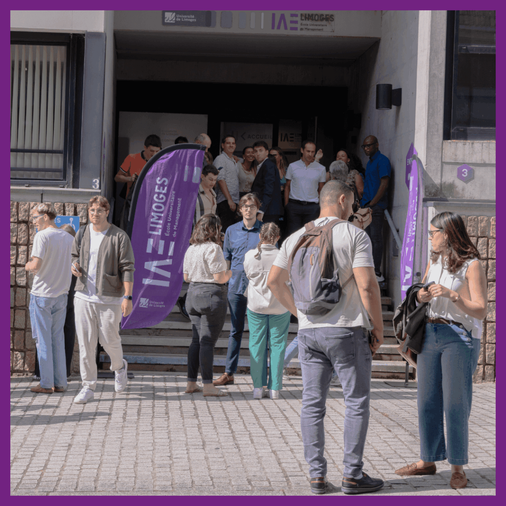 Étudiants rassemblés devant l’entrée de l’IAE Limoges à l’occasion de la rentrée universitaire, sous un temps ensoleillé, avec des drapeaux violets portant le logo de l’école.